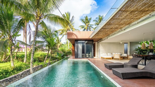 A modern pool area with a wooden deck, lounge chairs, and a glass-enclosed room. - Green Flow Villa 20 (Ubud)