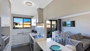 Una cocina moderna con ventana, comedor con mesa y sillas, y un sofá.