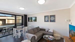 Una sala de estar moderna con un sofá, una mesa de centro de vidrio y un comedor con sillas y una mesa.