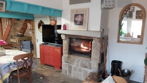 A cozy living room with a stone fireplace, wooden furniture, and a television.