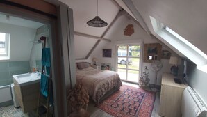 A bedroom with a bed, a desk, a window, and a door.