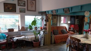 A cozy living room with a sofa, a dining table, and various plants.