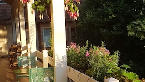 Un espace extérieur abrité, aménagé avec des chaises en métal vert et une clôture blanche.