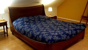 Une chambre avec un lit en bois, une table de chevet avec une lampe et un plancher en bois.