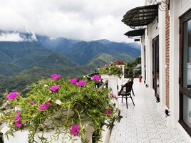Un balcón con vistas a montañas, una mesa con sillas y un letrero que indica una salida.