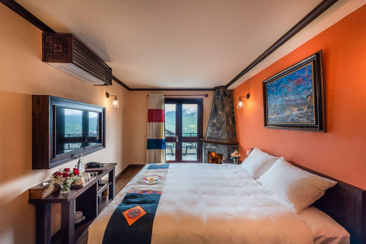 Ein Hotelzimmer mit einem großen Bett, einem Fernseher, einem Kamin und Blick ins Freie.