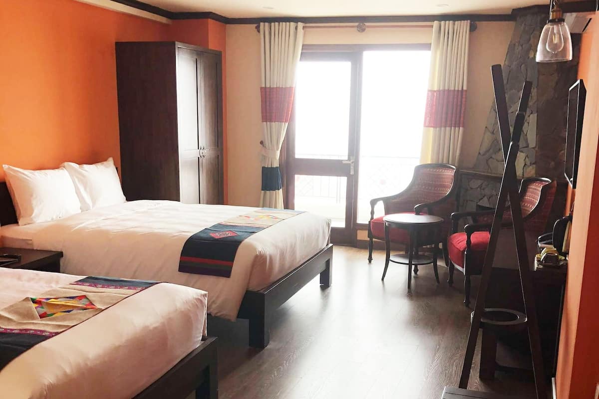 Ein Hotelzimmer mit zwei Betten, einem Schreibtisch und einem Stuhl.