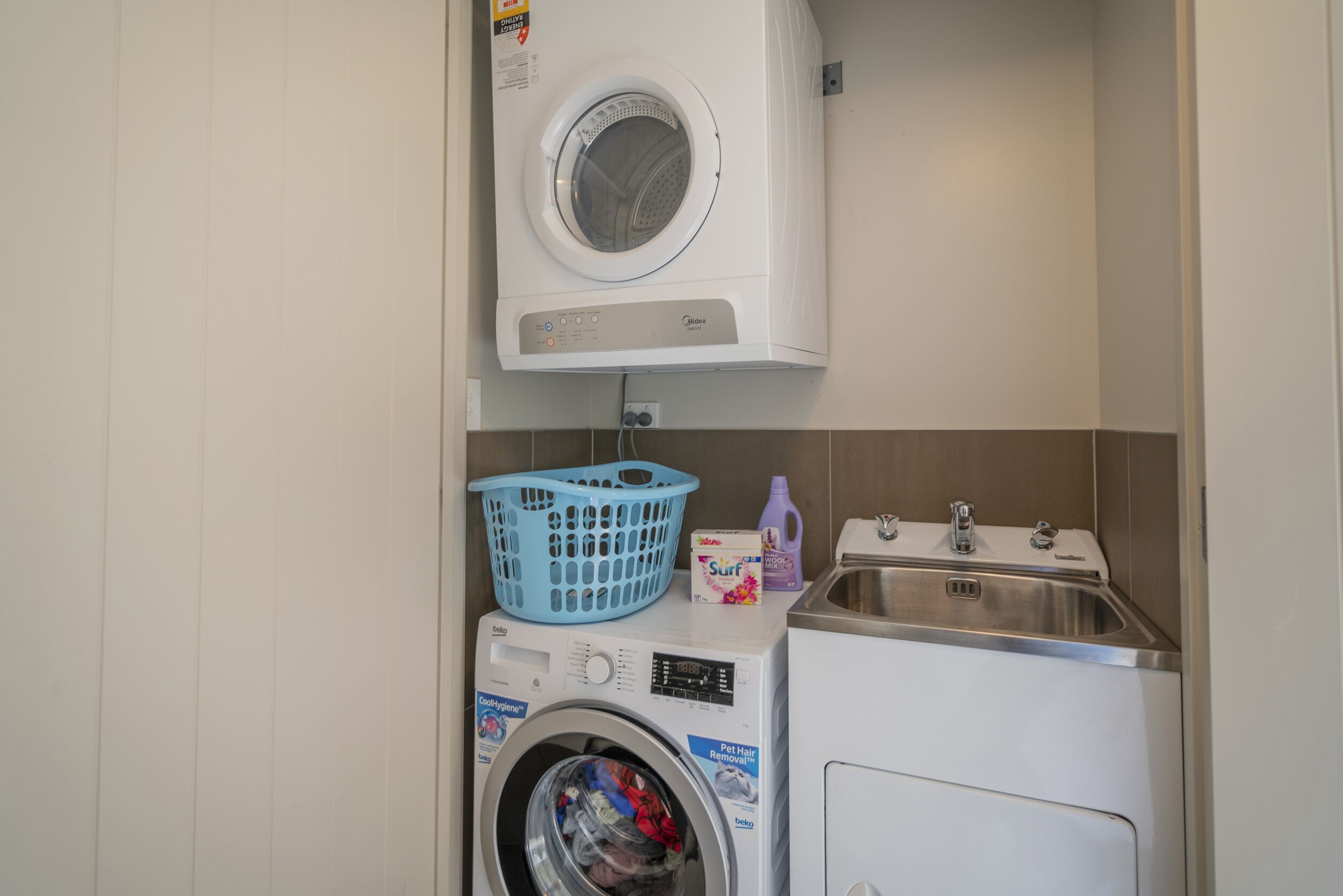 A compact laundry area with a front-loading washing machine, a dryer, and a sink.