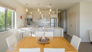 A modern kitchen with white cabinetry, a central island, and pendant lighting. - Great Matarangi Location Lakeside Gem overlooking the golf course! (Matarangi)