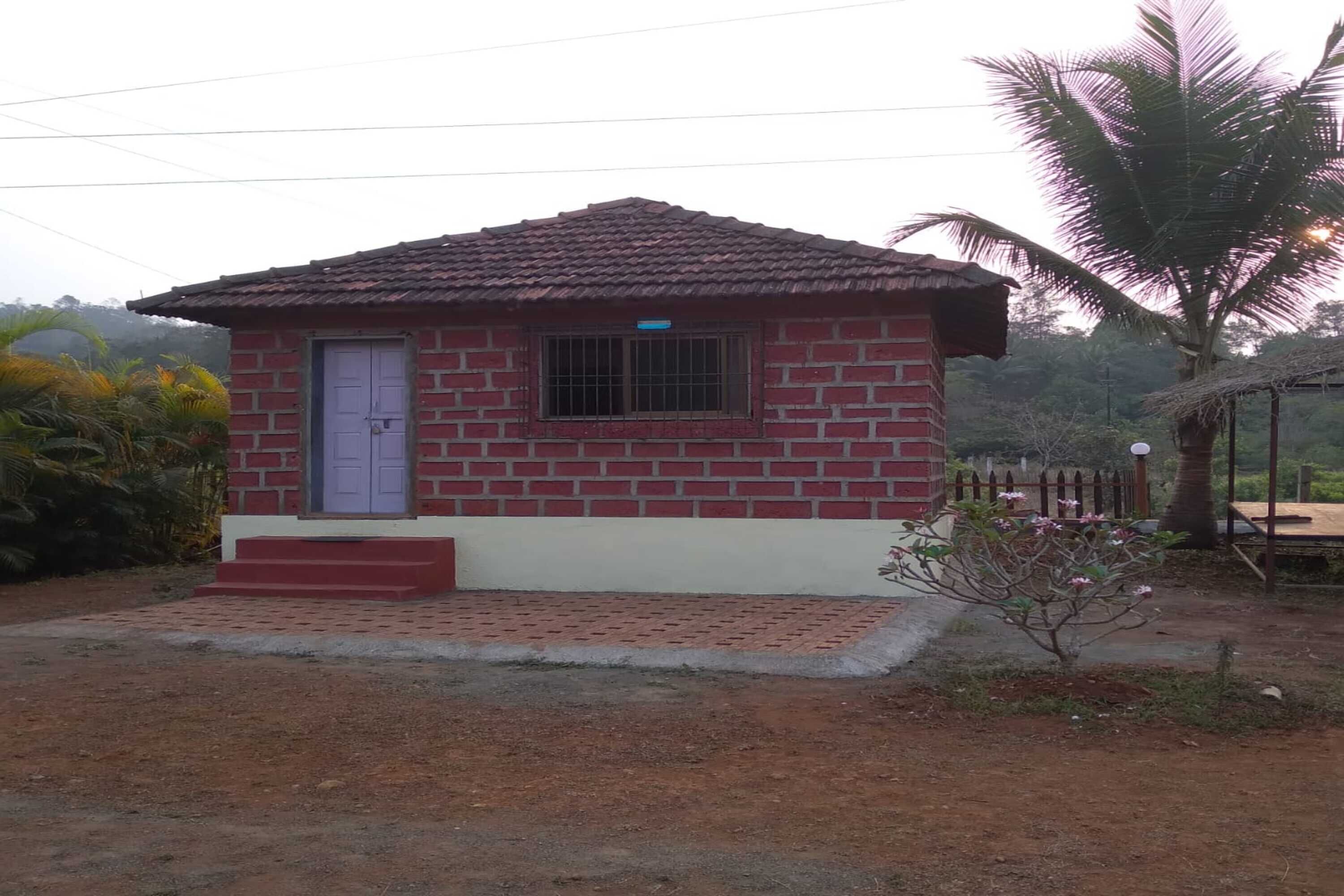 A small brick house with a tiled roof, a single window, and a door.