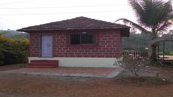 A small brick house with a tiled roof, a single window, and a door.