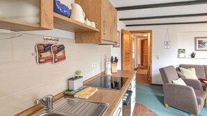 Een keuken met houten kastjes, een roestvrijstalen spoelbak en een aanrecht met diverse keukenspullen.