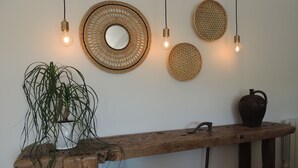 Ein Holzkonsolentisch mit einer Topfpflanze, einer dunklen Vase und einem rustikalen Wandbehang.