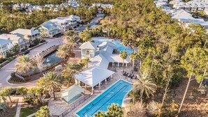 An aerial view of a resort with multiple buildings, a swimming pool, and surrounding palm trees. - Beargrass -Luxury NatureWalk Home - Golf Cart (Santa Rosa Beach)