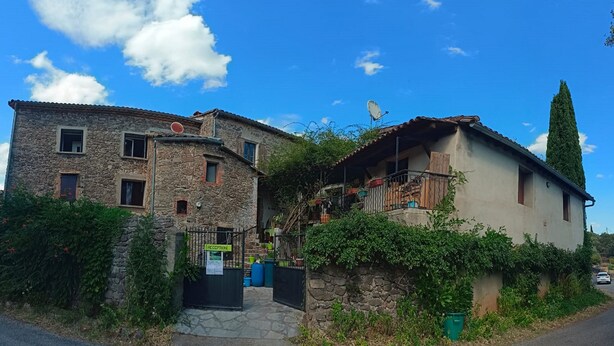 Un edificio de piedra con recepción, un balcón y un árbol alto cercano.