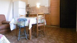 Una cocina compacta con una mesa de comedor, sillas, un refrigerador y un mueble de madera.