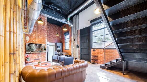 Ein stilvoller Wohnraum mit Backsteinwand, einer Ledersofa und einer Treppe.