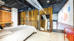 Ein modernes Hotelzimmer mit einem großen Bett, einer Holzwand und einer roten Metallbank.