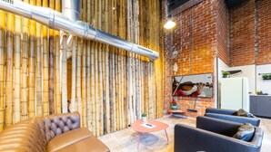 Ein moderner Lounge-Bereich mit Ledersofas, einer Bambuswand und einer Wand aus Backsteinen.