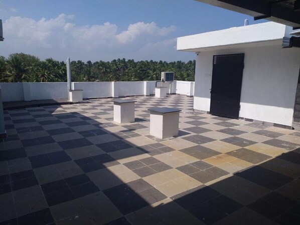 A rooftop terrace with a checkered floor, a few seating areas, and a door to a building. - Hotel Rani and Rani Residency (Vanur)