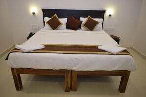 A large bed with a wooden frame, white bedding, and two bedside lamps. - Hotel Rani and Rani Residency (Vanur)