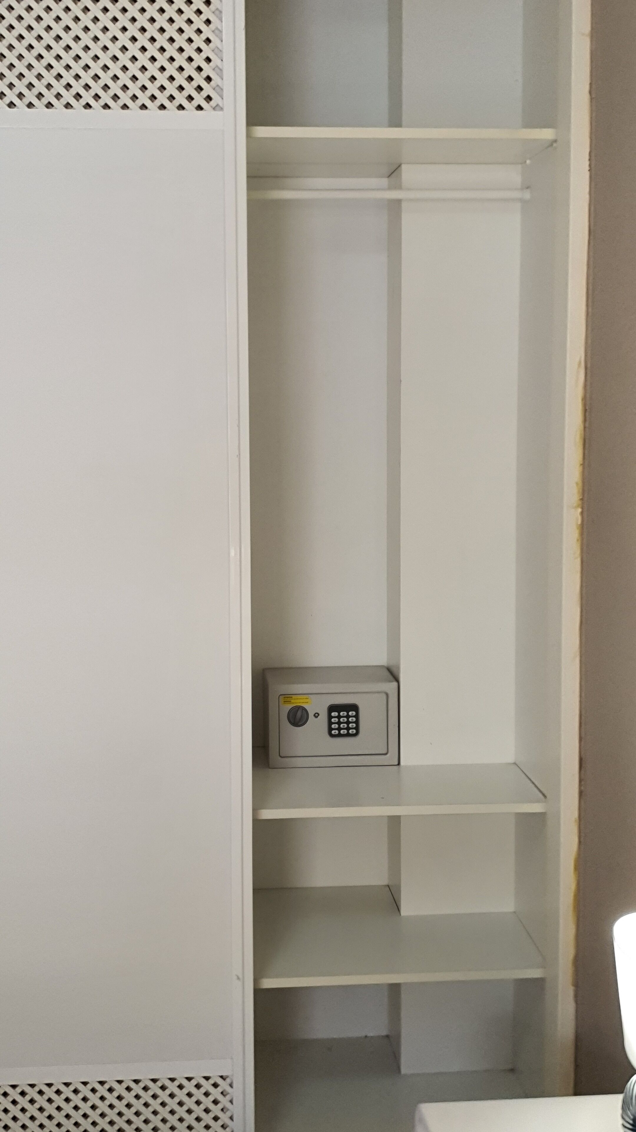 A white storage closet with multiple shelves and a small safe.