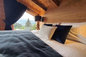 Ett sovrum i en stuga, inrett med en säng, kuddar och ett nattduksbord.