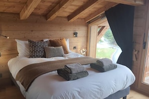 A wooden cabin bedroom with a large bed, pillows, and a blanket.