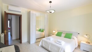 A hotel room with a bed, bedside lamps, a wardrobe, and a desk with a chair.