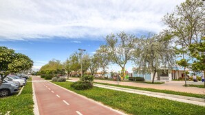 A paved pathway with a red bike lane, lined with trees and grass, leading to a building with a blue facade.