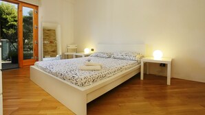 A modern bedroom with a large bed, wooden flooring, and a glass door leading to an outdoor area. - Sicily 2 - 3 - 4 Person With Pool (Altavilla Milicia)