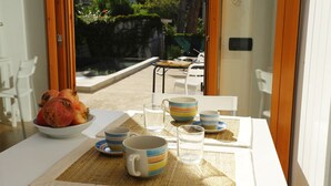 A dining area with a table set for two, featuring a bowl of fruit and striped tableware. - Sicily 2 - 3 - 4 Person With Pool (Altavilla Milicia)