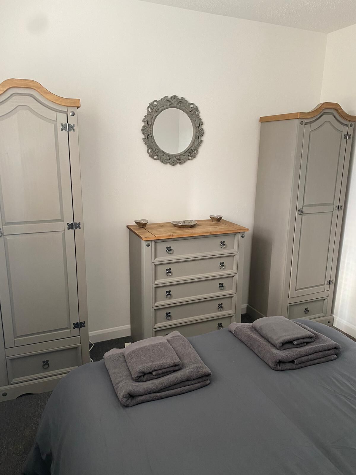 Une chambre à coucher avec un lit, deux commodes et un miroir accroché au mur.