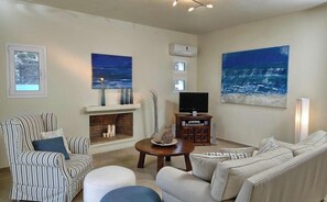 A living room with striped furniture, a fireplace, a television, and two large paintings.
