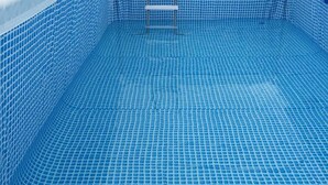 A swimming pool with a tiled floor and walls, and a small white structure in the center. - Rasta Tees Place - Standard (Adenta)