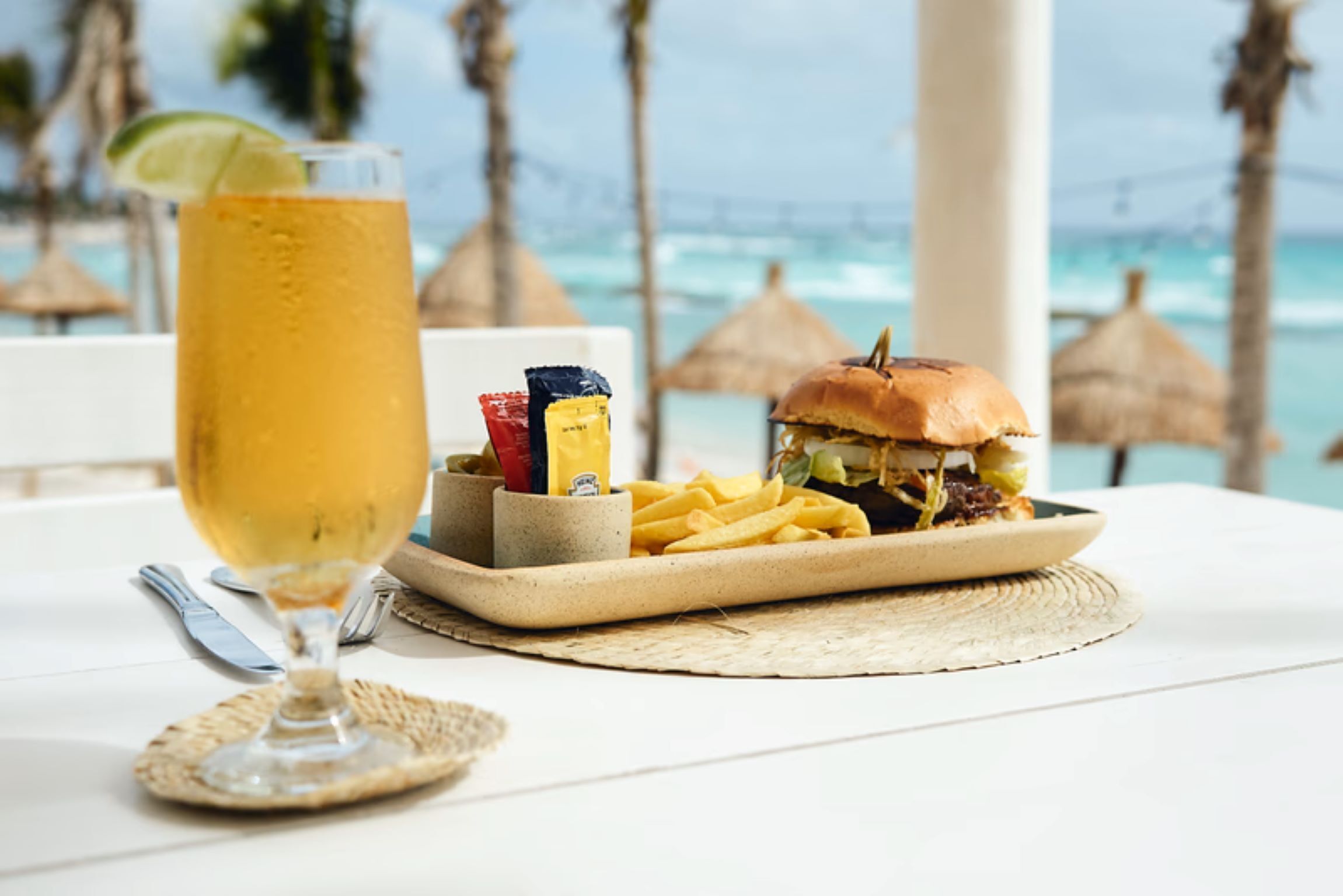 Ein Tisch mit einem Getränk, einem Burger, Pommes und Beilagen.