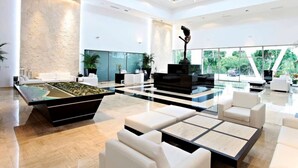 Un salón moderno y espacioso con un gran ventanal, una mesa de billar y cómodos asientos.