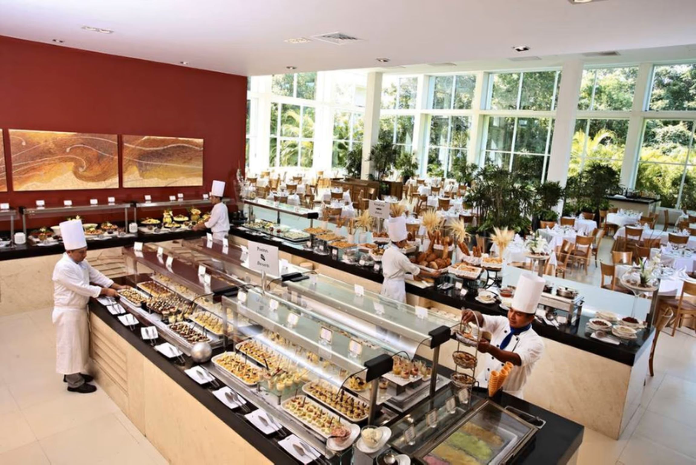 Un'area buffet con diverse postazioni di cibo, uno chef che cucina e vista all'esterno attraverso ampie finestre.