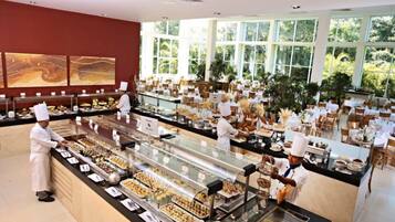 Un'area buffet con diverse postazioni di cibo, uno chef che cucina e vista all'esterno attraverso ampie finestre.