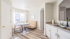 A modern kitchen with a dining area, featuring a round table, a cushioned bench, and a large window providing natural light. - Three bed two bath, gas grill, king bed (Tucson)