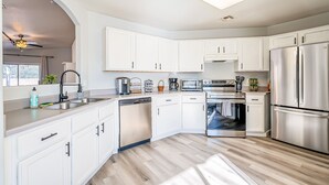 A modern kitchen with white cabinets, stainless steel appliances, and a dishwasher. - Three bed two bath, gas grill, king bed (Tucson)