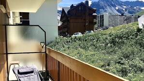 A balcony with a chair and a metal railing overlooking a mountainous landscape with buildings. - Studio Dans une Petite Copropriété en Plein Centre de Tignes (Tignes)
