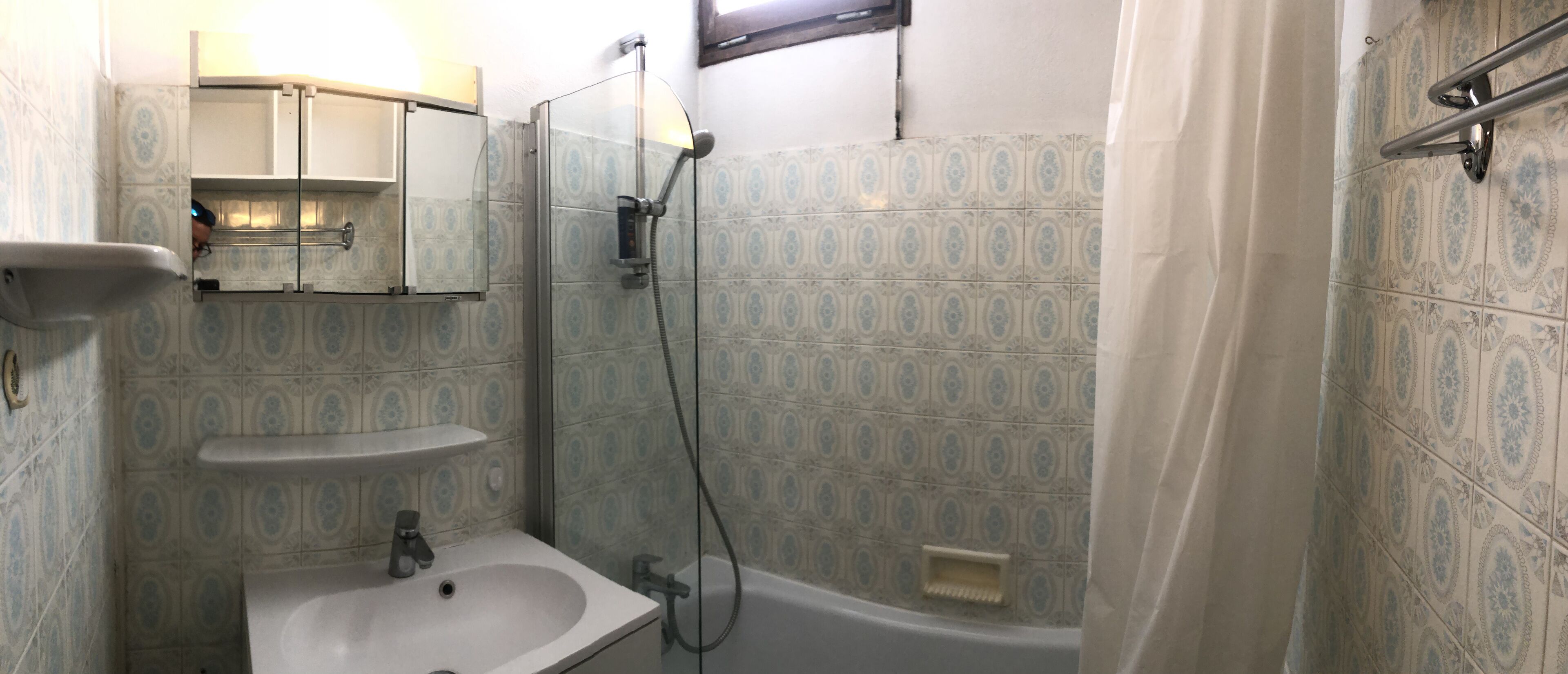 A bathroom with a sink, mirror, and shower.