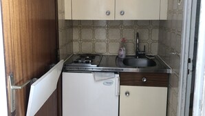 A compact kitchen with a refrigerator, sink, and wooden cabinets. - Studio Dans une Petite Copropriété en Plein Centre de Tignes (Tignes)