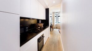 Una cocina moderna con armarios blancos, encimera negra y horno empotrado.