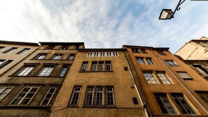Un edificio de varios pisos con fachada desgastada, múltiples ventanas y una farola.