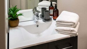 Un baño moderno con un espejo grande, un lavabo blanco y una cabina de ducha de vidrio.