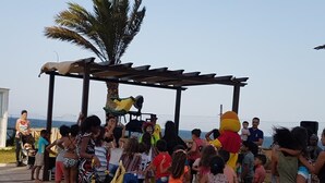 Un gruppo di persone radunate attorno a una struttura in legno, con una persona in costume giallo.