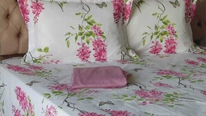 Un letto con una coperta a fiori e due cuscini con lo stesso motivo.