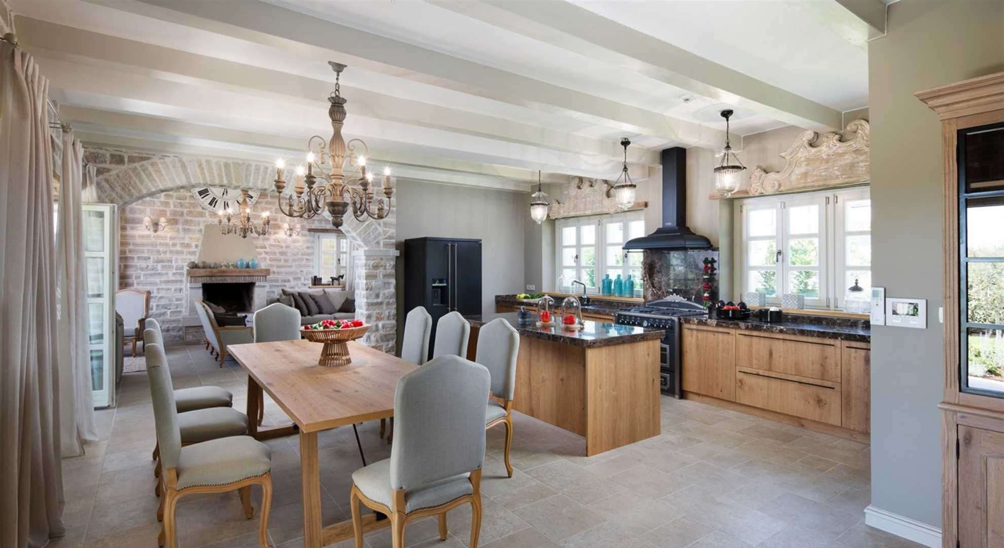 A spacious kitchen with a large island, a dining area with a wooden table and chairs, and a stone fireplace.